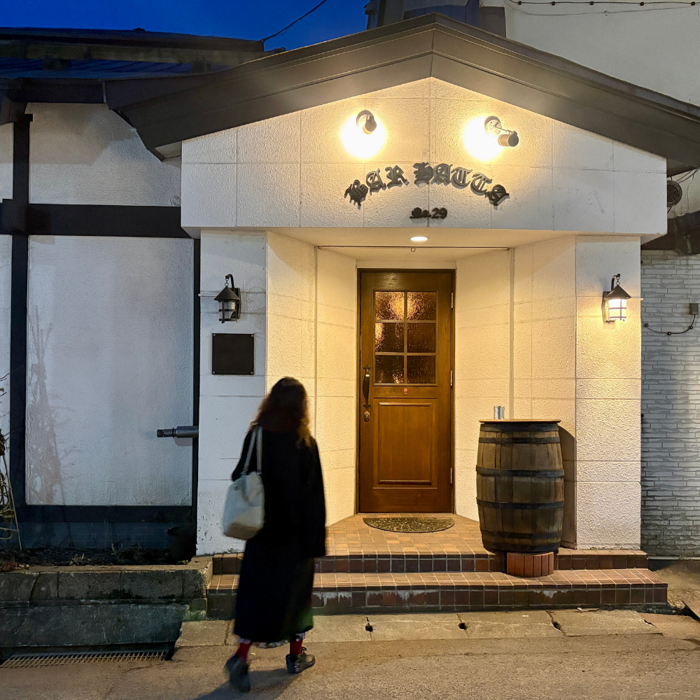 「THE BAR HATTA」の入り口。白い壁にクラシックな街灯と木製のドアが印象的な外観