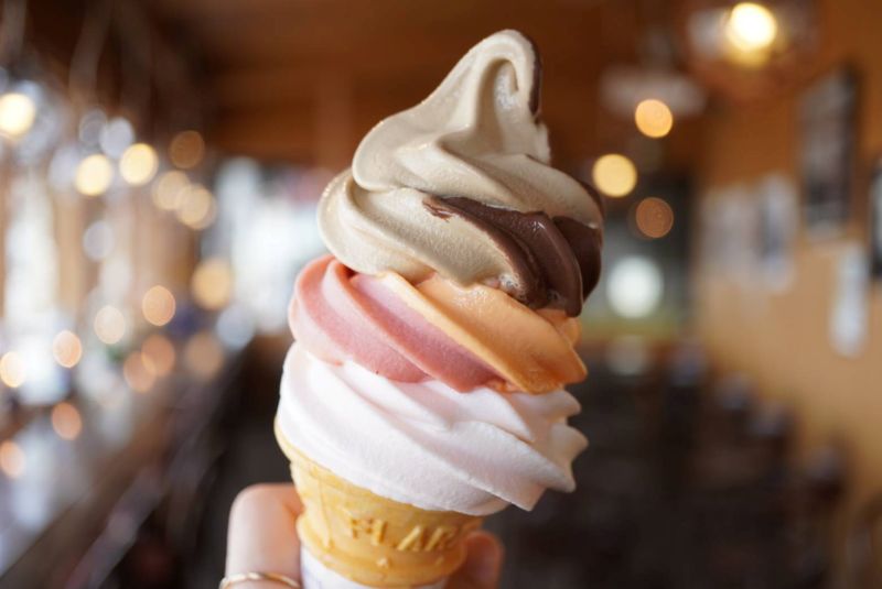 北一硝子三号館テラスの、カラフルな6色ソフトクリーム「スペシャルミックス」を手に持っている写真