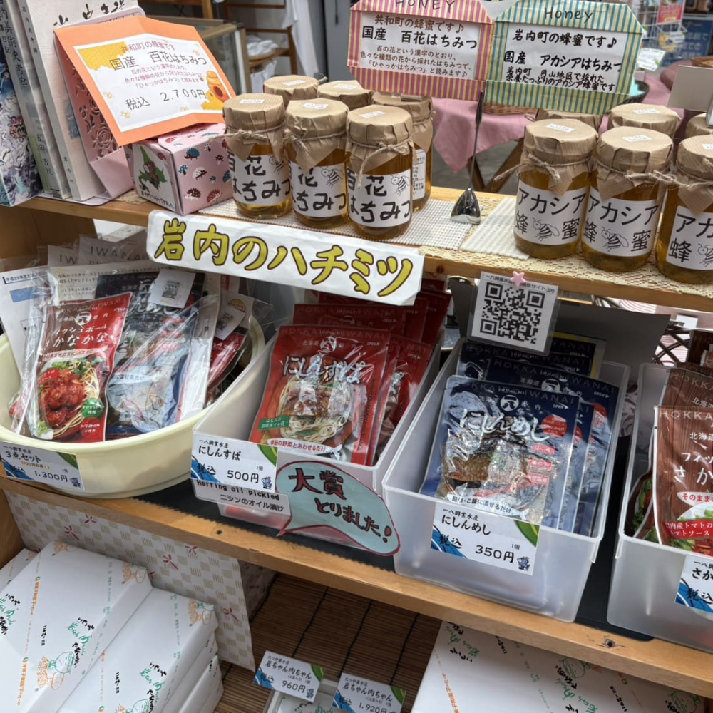 「道の駅いわない」の店内に並ぶ、地元産の「百花はちみつ」や「アカシアはちみつ」の瓶詰めと、手書きの「岩内のハチミツ」ポップ