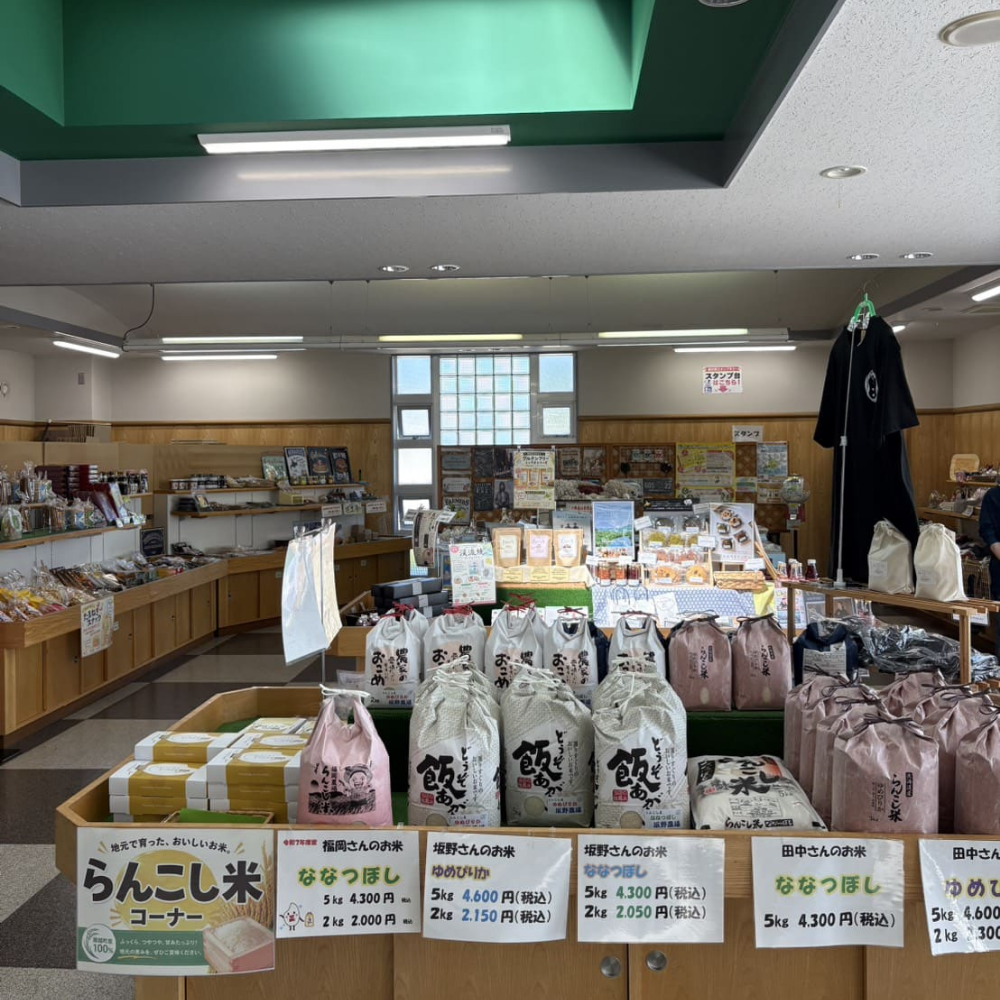 「シェルプラザ・港」の店内にある特産品コーナー。「らんこし米」の米袋が並ぶ棚と、その奥に陳列された加工品やオリジナルTシャツ