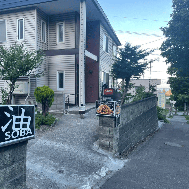 「NOODLE rafe」の敷地入口。「油 SOBA」の看板と坂道沿いに建つ一軒家風の店舗アプローチ