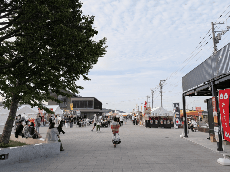 潮まつり会場に新しくオープンした「おたるポートスクエア」の広場で、白テントの出店が立ち並び多くの人々が行き交う様子