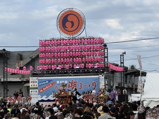 ピンクの提灯が並ぶ「第60回おたる潮まつり」のメインステージ前に複数の神輿が集結し、大勢の観客が見守る中で熱気を見せる「神輿パレード」宮入りの様子