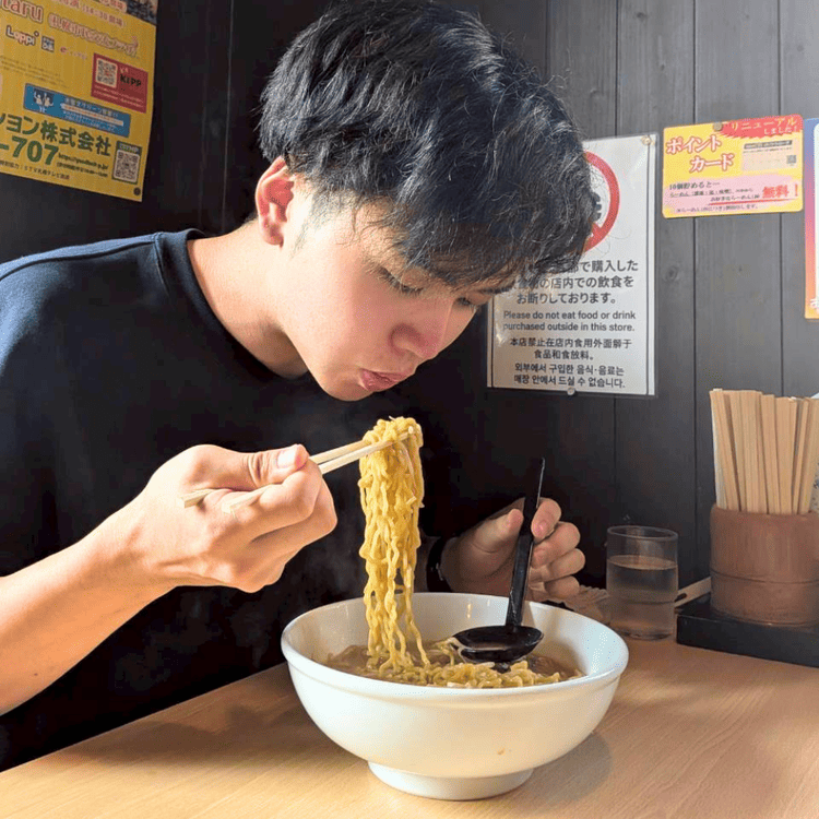 「おたる蔵屋」の店内で、学生ラーメンを勢いよくすする大学生の様子