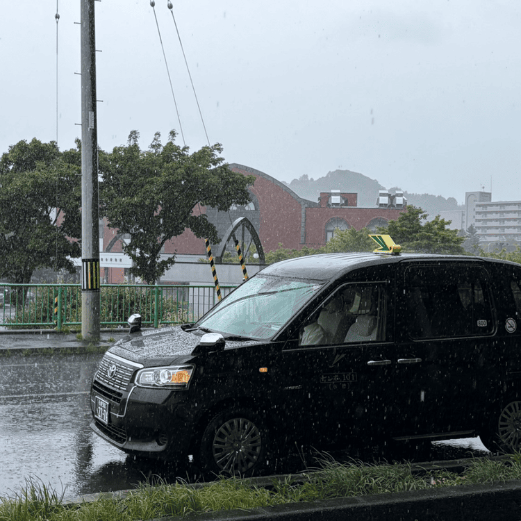 激しい雨が降る小樽市総合博物館本館前と停車する観光タクシー