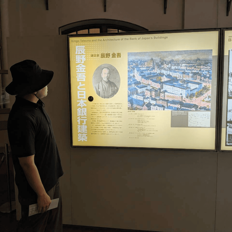 金融資料館（旧日本銀行小樽支店）で建築家・辰野金吾の解説パネルを見る様子